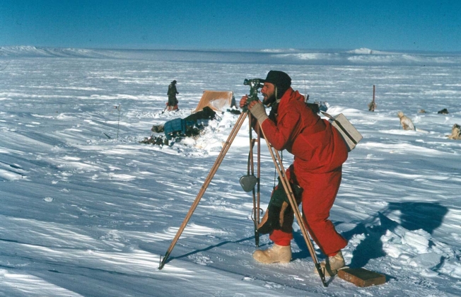 Photo by Richard Ruker. Syd Kirkby using a theodolite in Enderby Land 1960